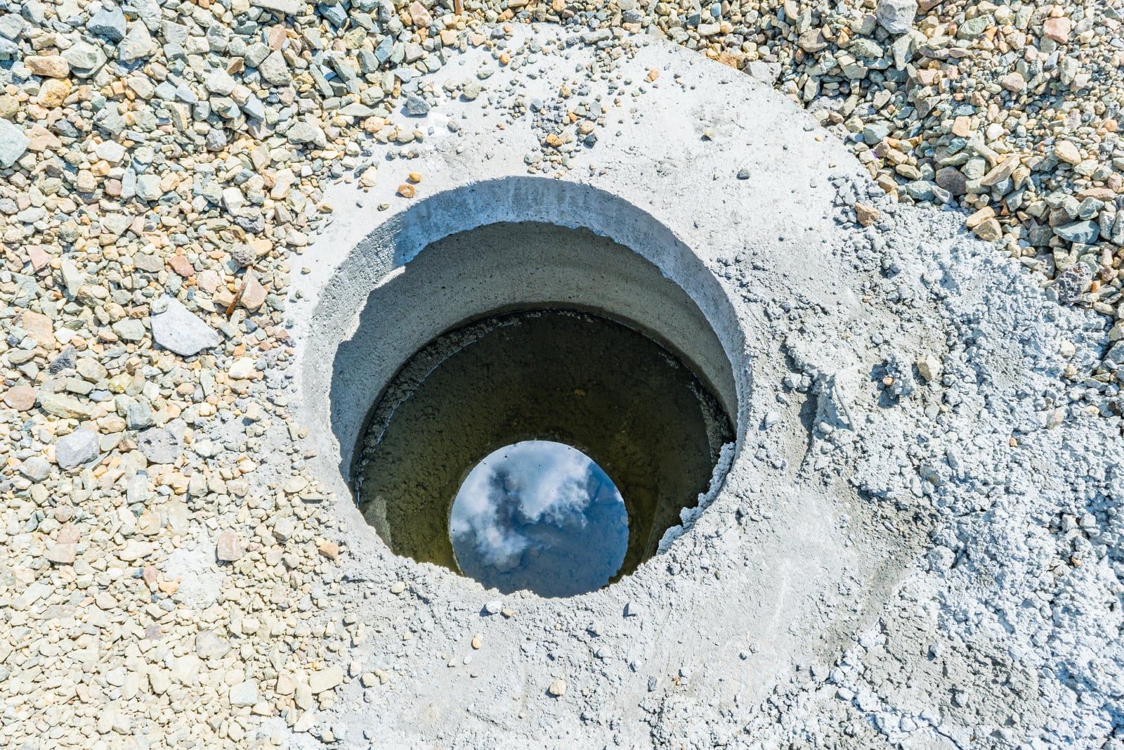 Rund betonbrønd sat ned i grus, klar til at lede regnvand videre